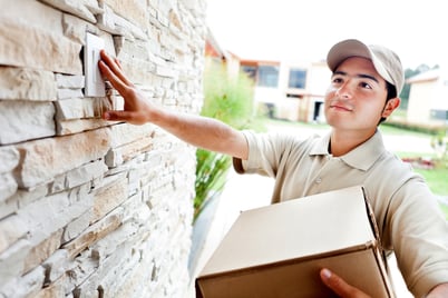 Happy delivery man outdoors ringing house doorbell