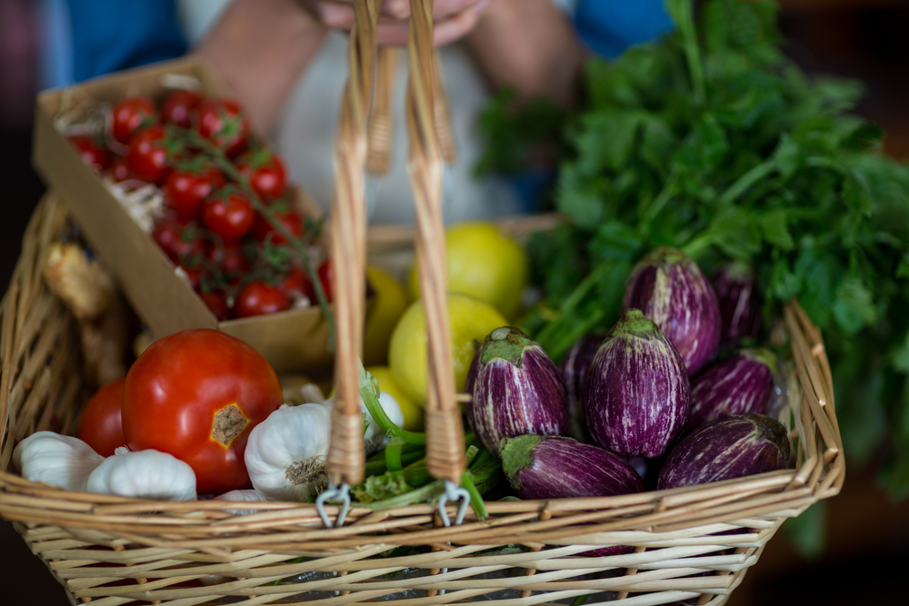 Close-up of female staff holding basket of vegetables in organic section of supermarket-2