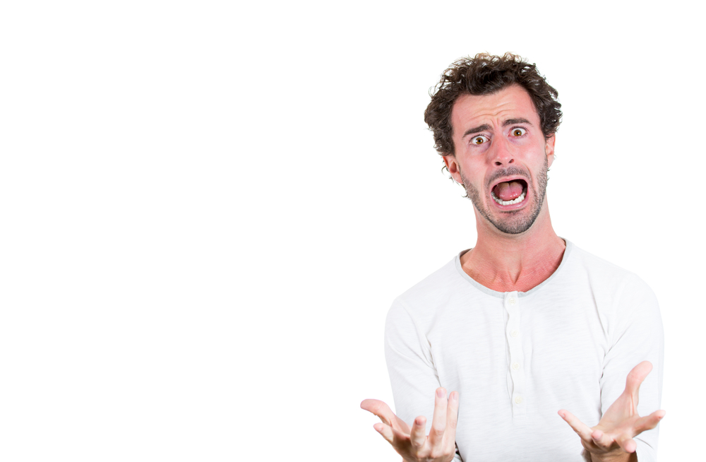 Closeup portrait of handsome young guy, worker or student looking stressed out and desperate asking why me, what have I done, why do i deserve all these? Isolated on white background with copy space.