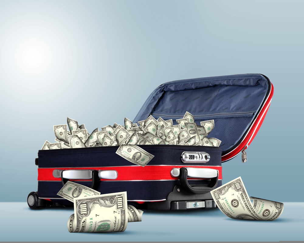 Picture of red travel suitcase full of banknotes