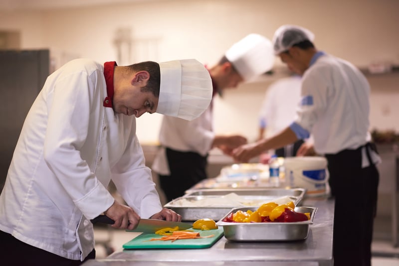 chef in hotel kitchen slice vegetables with knife and prepare food